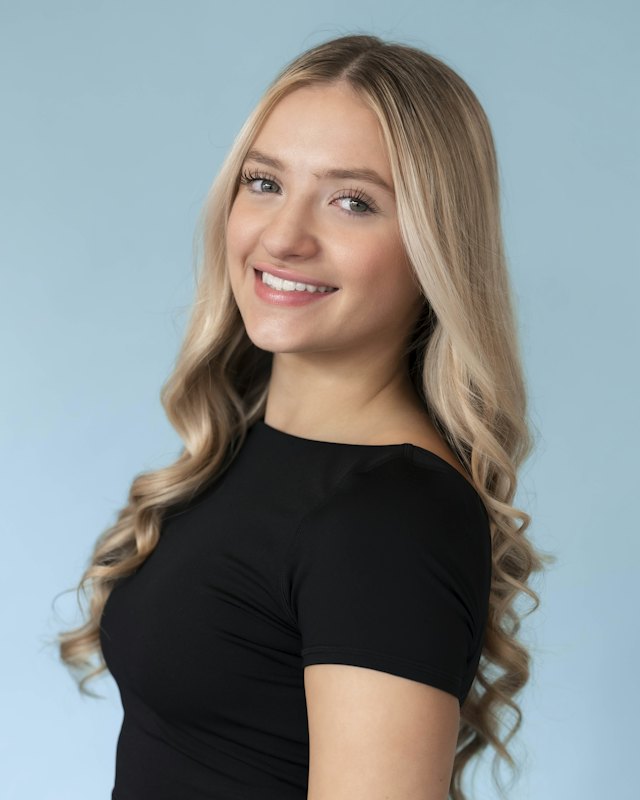 Person with light cool skin and blonde hair, draped in Orange